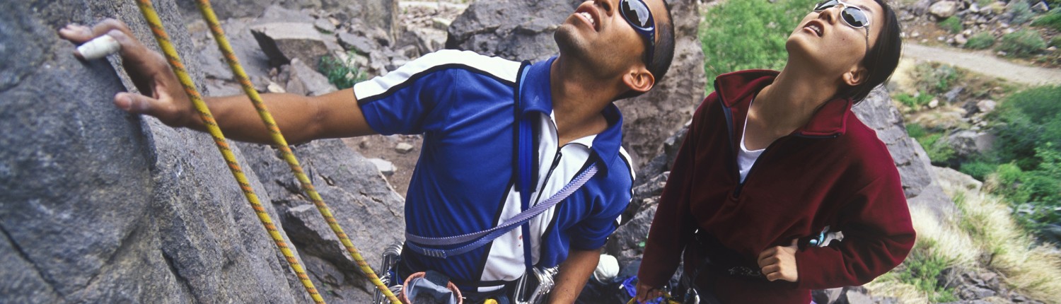 two people wearing sunglasses rock climbing to stay healthy